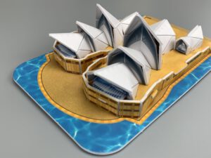 Sydney Opera House model with white sail-like roofs and blue harbour pool base, angled view.