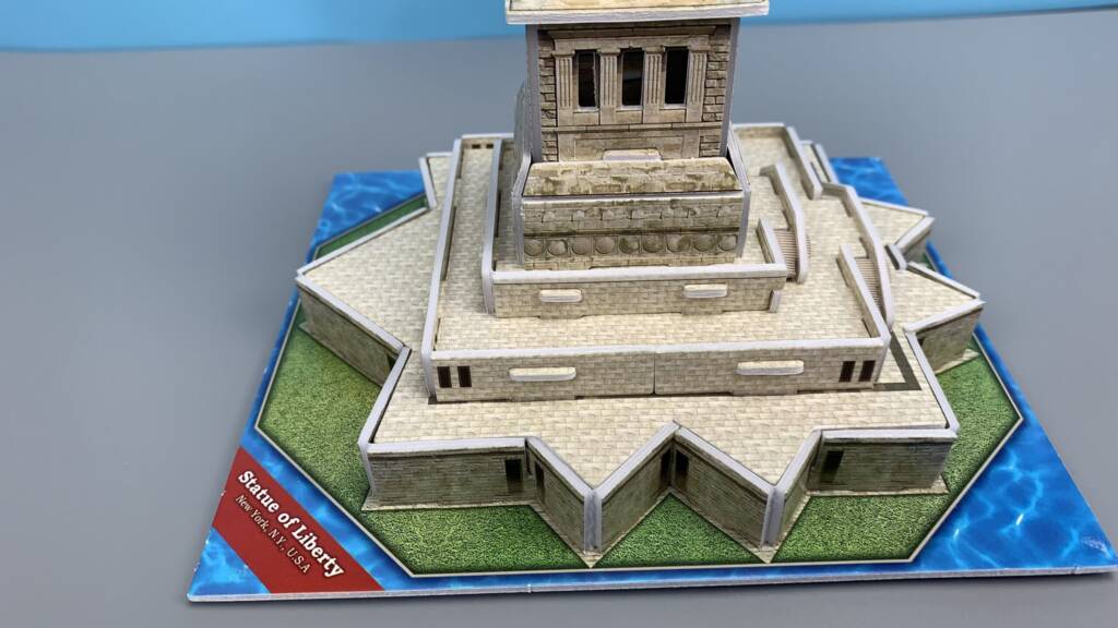 Statue of Liberty miniature, detailed base on a blue display platform with “Statue of Liberty” text label