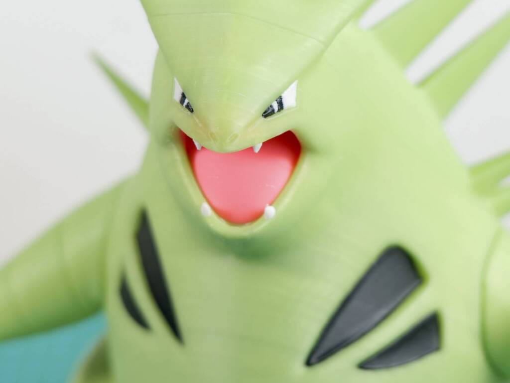Menacing green cartoon dragon with open red mouth and sharp teeth, close-up face illustration