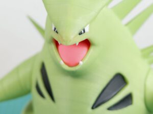 Menacing green cartoon dragon with open red mouth and sharp teeth, close-up face illustration