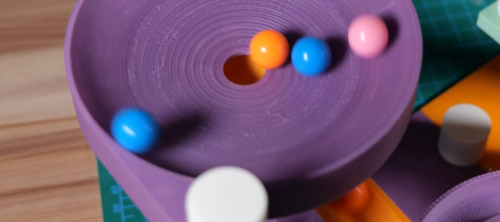 Purple marble run track with colorful marbles rolling through a spiral channel