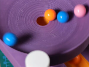 Purple marble run track with colorful marbles rolling through a spiral channel