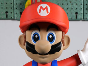 Super Mario with red cap and “M” logo, mustache and blue overalls giving a thumbs-up