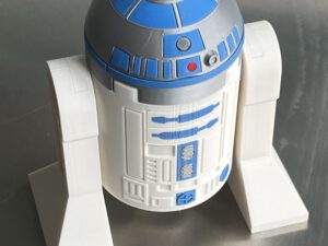 Large LEGO R2-D2 droid head with blue details and cylindrical top on a display stand