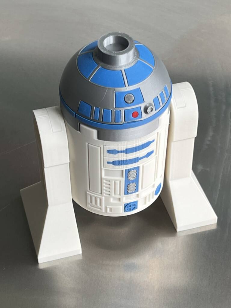 Large LEGO R2-D2 droid head with blue details and cylindrical top on a display stand