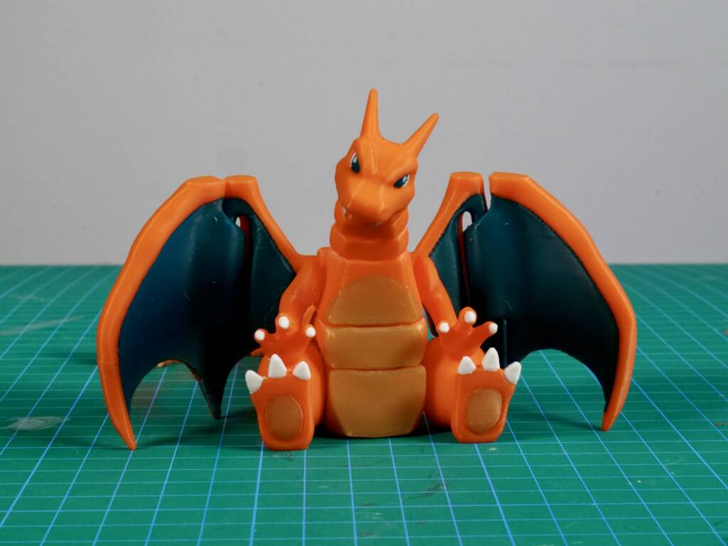 Charizard flexi articulated Pokémon figure with open wings on a green cutting mat