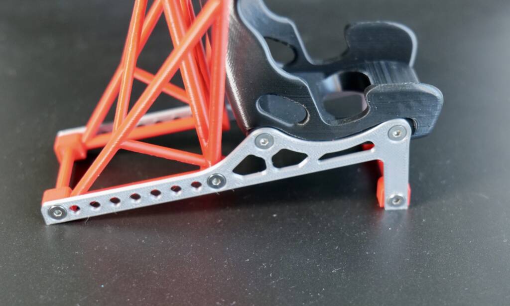 Metal car jack linkage with red support frame on dark surface