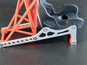 Metal car jack linkage with red support frame on dark surface