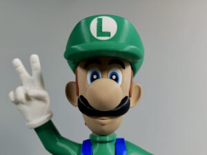 Luigi in green hat and blue overalls making a peace sign with his gloved hand