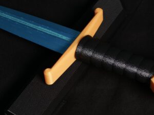 Medieval dagger with blue blade, orange crossguard, and black leather-wrapped handle on dark background