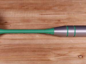 Giant dart with green shaft and silver barrel on a wooden floor, tip pointing right